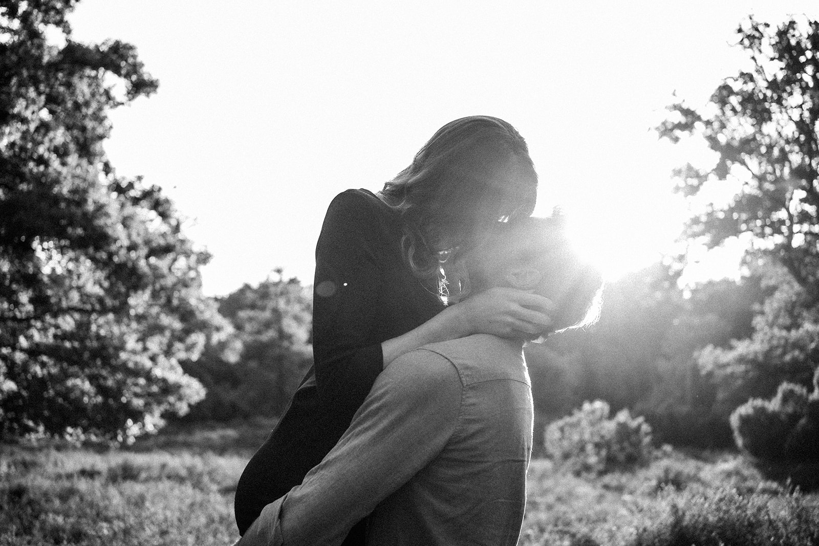 Romantischer Kuss bei einem Paarshooting in Ahaus, Sonnenlicht und Schwarz-Weiß-Ästhetik in der Natur.