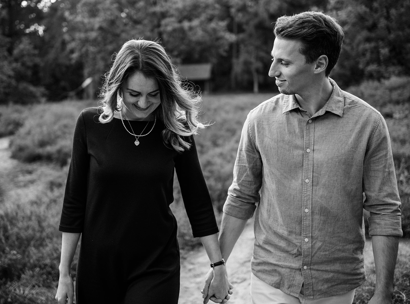 Verliebtes Paar beim Paarshooting in Ahaus, hält sich lächelnd an den Händen, stilvolle Schwarz-Weiß-Aufnahme.