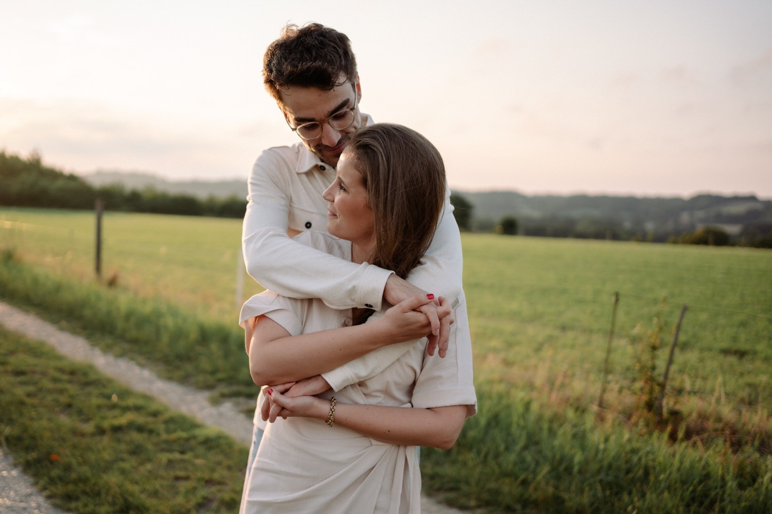 Verliebtes Paar bei einem Paarshooting in Ahaus, innige Umarmung in der Natur bei Sonnenuntergang.