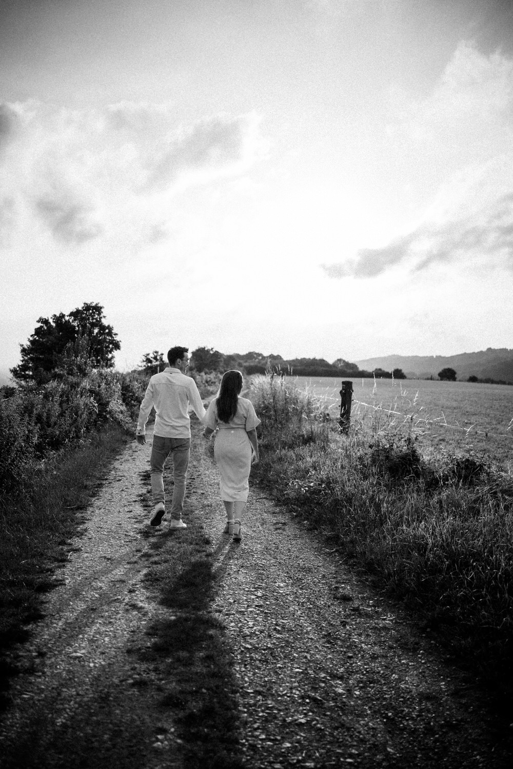Paar beim Fotoshooting in Ahaus, Hand in Hand auf einem Feldweg, romantische Schwarz-Weiß-Aufnahme.