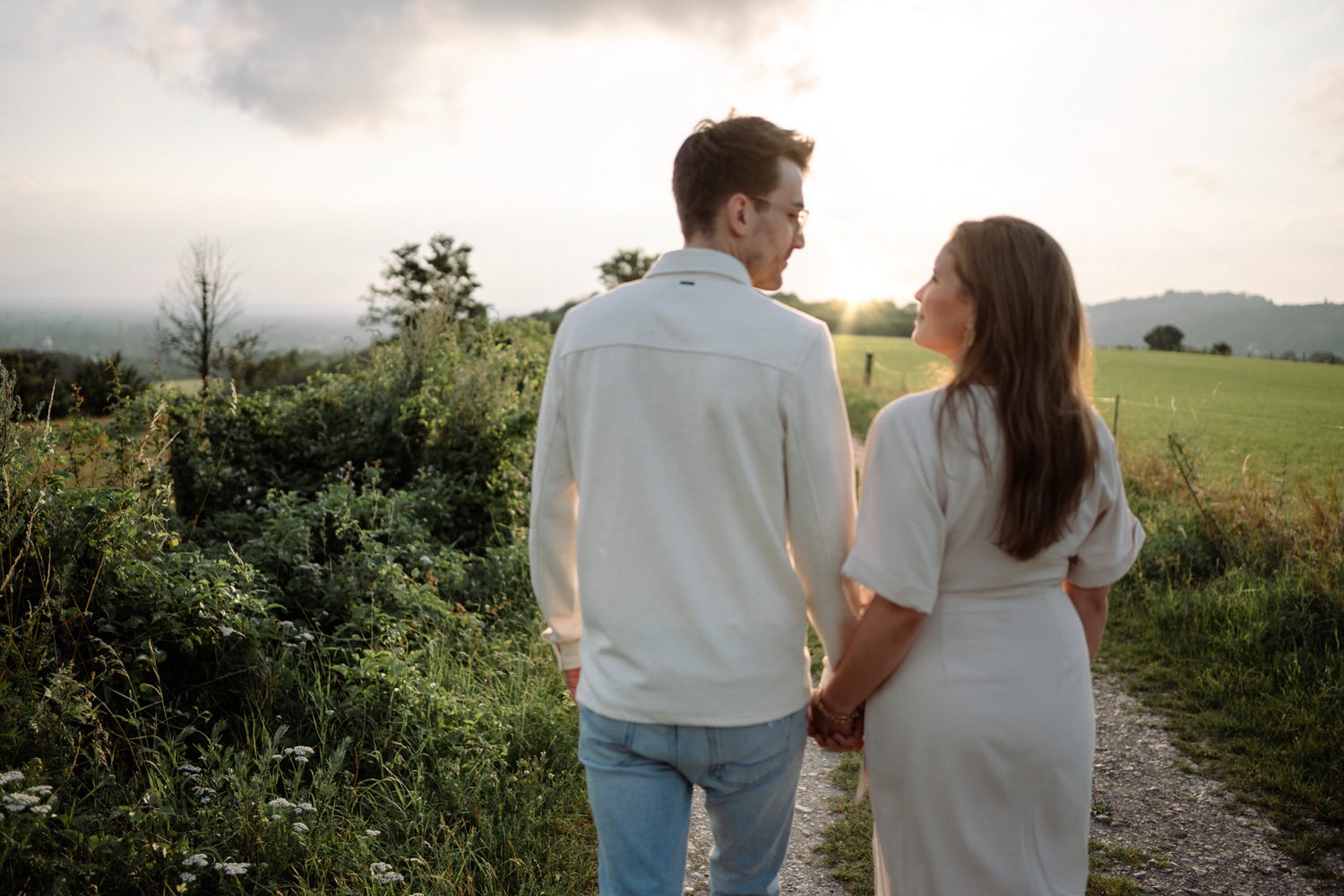Paar beim Paarshooting in Ahaus, Hand in Hand auf einem Feldweg bei goldenem Sonnenuntergang.