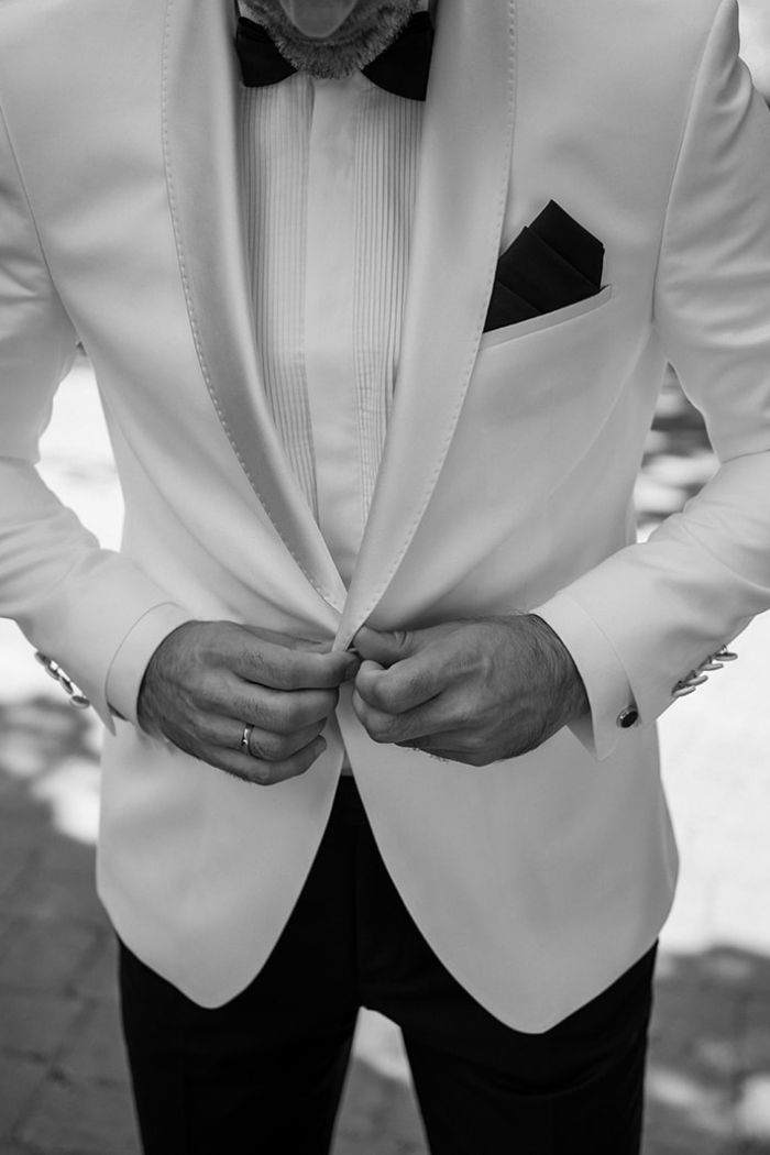 Bräutigam knöpft sein weißes Sakko zu, festgehalten in schwarz weiß – Hochzeitsfotograf Ahaus.