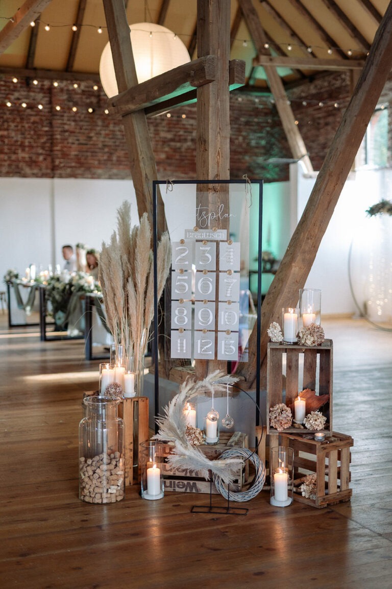 Stilvoll dekorierter Sitzplan mit Kerzen und Pampasgras bei einer Hochzeit in der See Scheune Buldern.