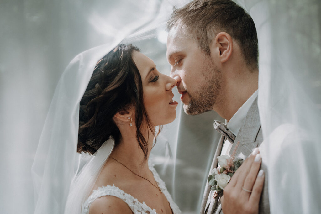 Brautpaar unter Schleier beim innigen Moment – Hochzeitsfotograf Ahaus