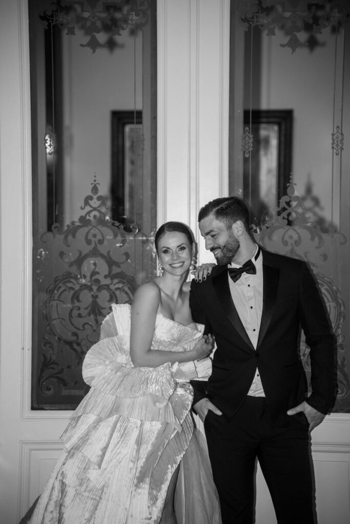 Verliebtes Brautpaar posiert elegant vor verzierten Türen in Ahaus fotografiert in schwarz weiß