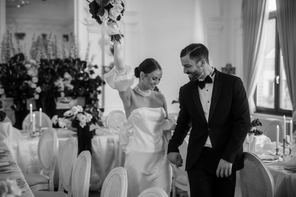 Brautpaar läuft lachend durch festlich dekorierten Hochzeitssaal in Ahaus fotografiert in Schwarz weiß