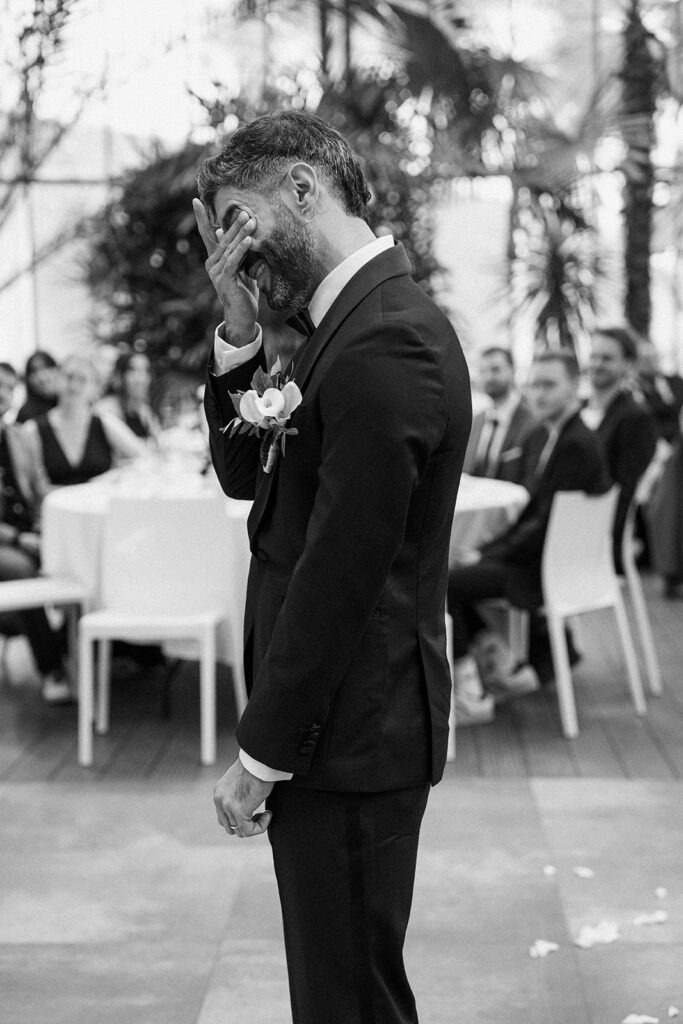Bräutigam reagiert gerührt während der Trauung vor den Hochzeitsgästen – Schwarz/Weiß fotografiert